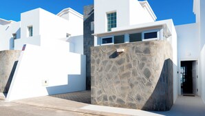 Un bâtiment moderne, de couleur blanche, avec une façade en pierre et un ciel d’un bleu éclatant.