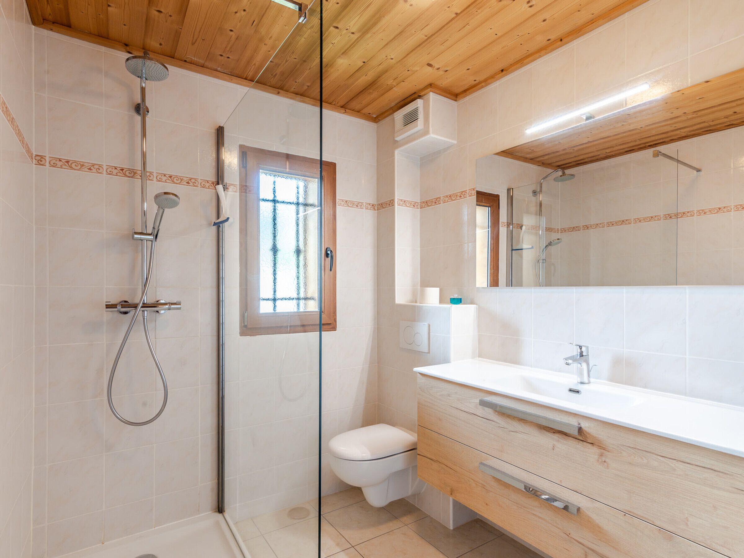 Een moderne badkamer met douche, toilet en wastafel.