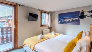 Una habitación de hotel con cama, televisión, ventana y un cuadro.