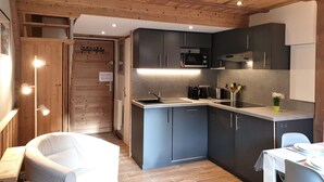 Una cucina moderna con mobili scuri, un forno a microonde e un lavello. C'è un'area pranzo con tavolo e sedie.