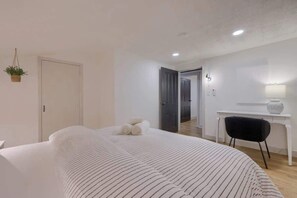 A bedroom with a bed, a desk, and a chair.