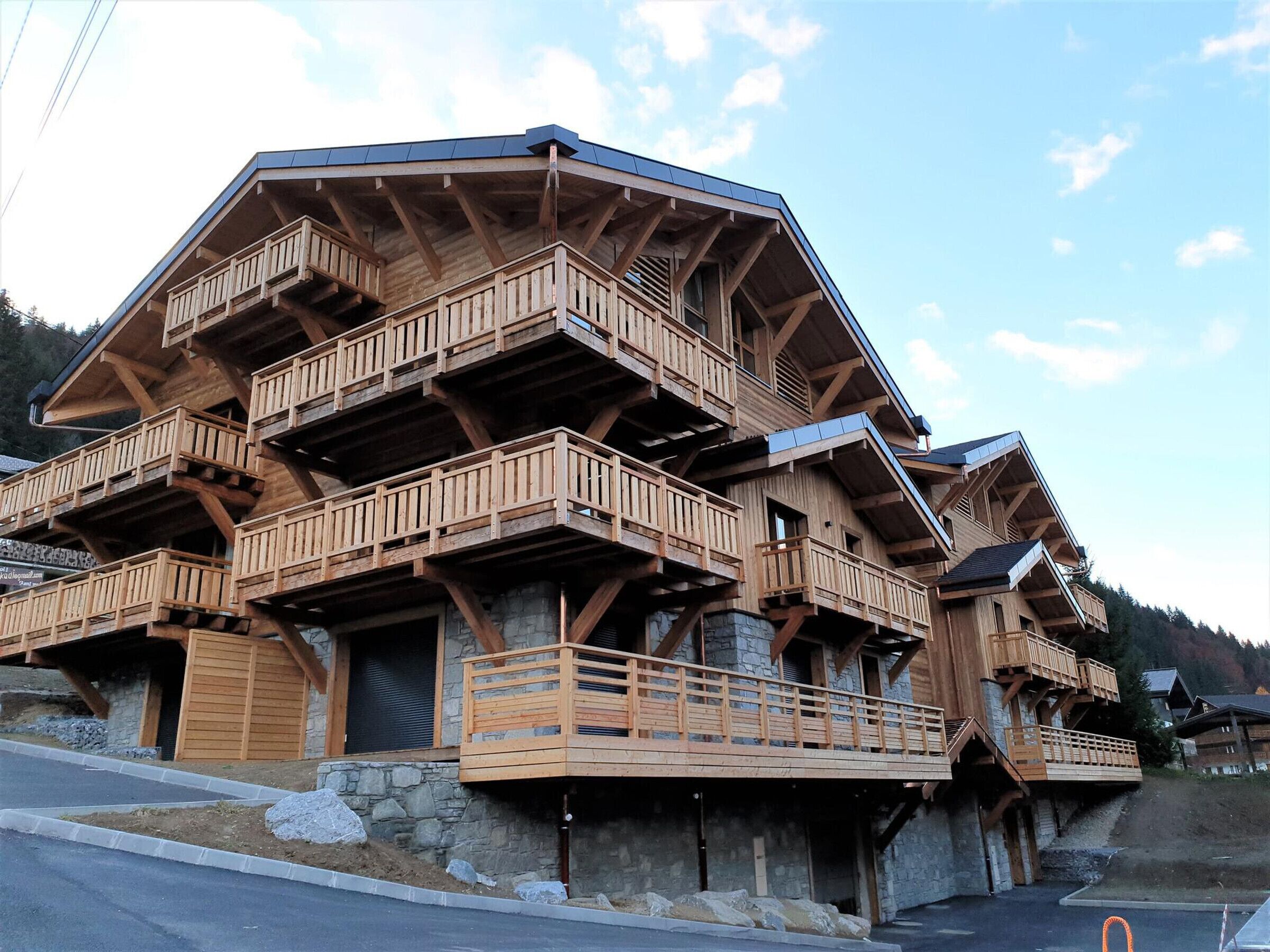 A multi-story wooden building with balconies, stone foundations, and a sloped roof.