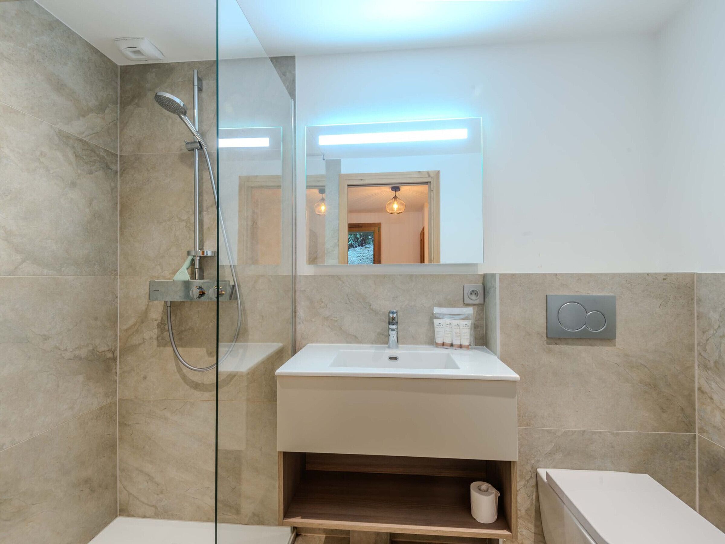 A modern bathroom with a glass-enclosed shower, a white sink, and a mirror above it.