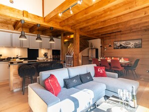 Relax in a spacious living area with a comfortable sofa, wooden staircase, and modern kitchen.