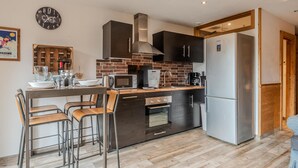 A modern kitchen with a central island, stainless steel appliances, and a brick backsplash. - Cosy T2 apartment with terrace 5 min from Avoriaz cable car (Morzine)
