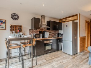A modern kitchen with a central island, stainless steel appliances, and a brick backsplash. - Cosy T2 apartment with terrace 5 min from Avoriaz cable car (Morzine)