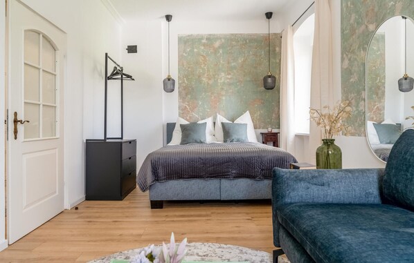 Classic design bedroom with a large bed, dresser, and textured wallpaper.