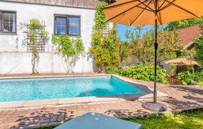 Relax by the serene pool surrounded by lush greenery and a shaded area.
