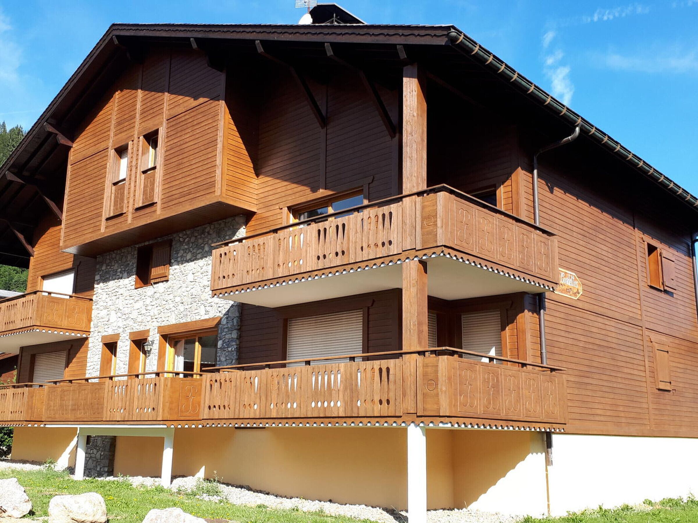 A wooden chalet with a stone facade, multiple balconies, and a sign indicating a restaurant.