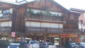 A multi-story building with a wooden facade, balconies with plants, and various storefronts. - Renovated studio-cabin for 4, central Morzine, near slopes (Morzine)