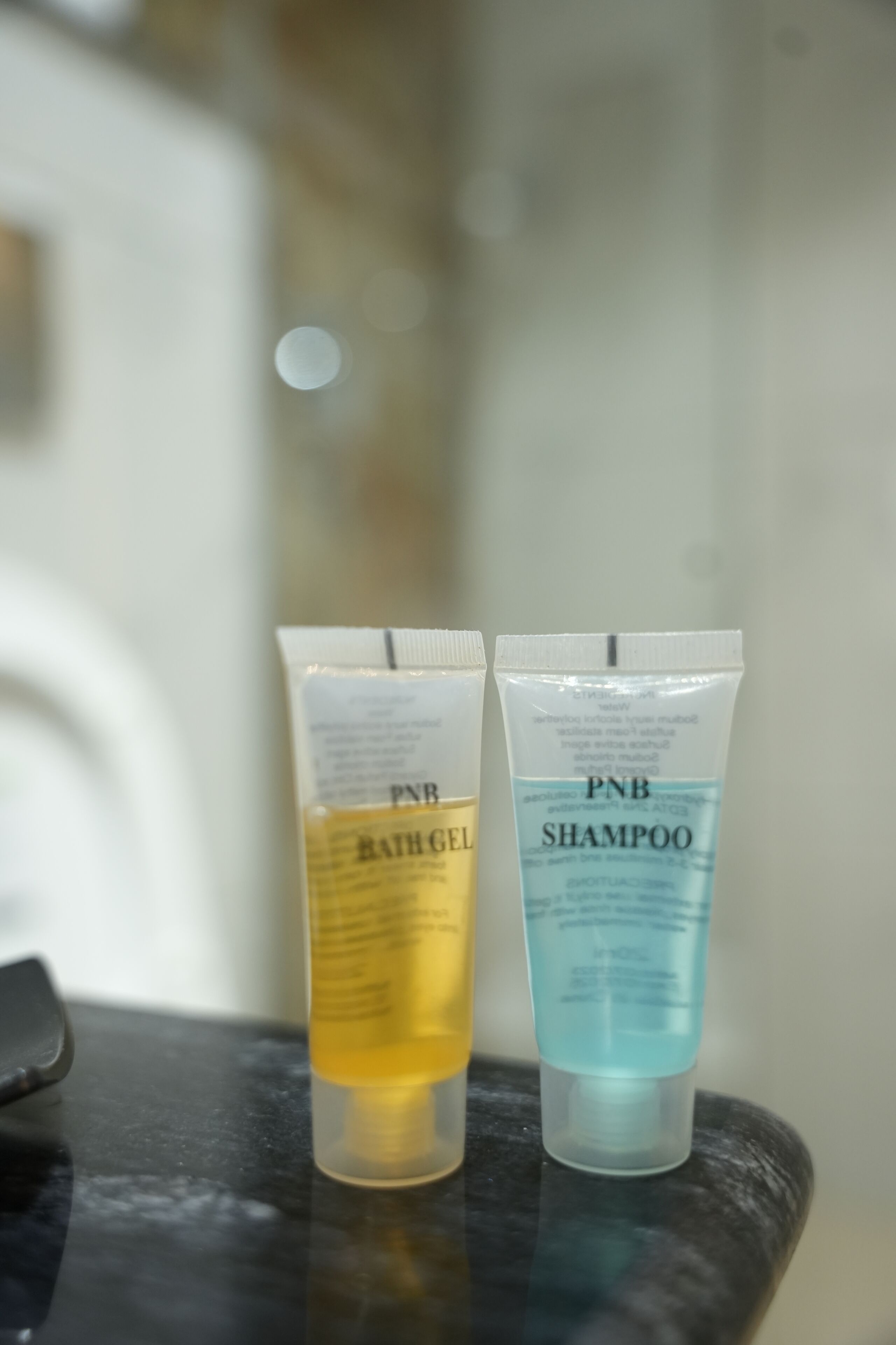 Two tubes of PNB shampoo and bath gel on a black surface.