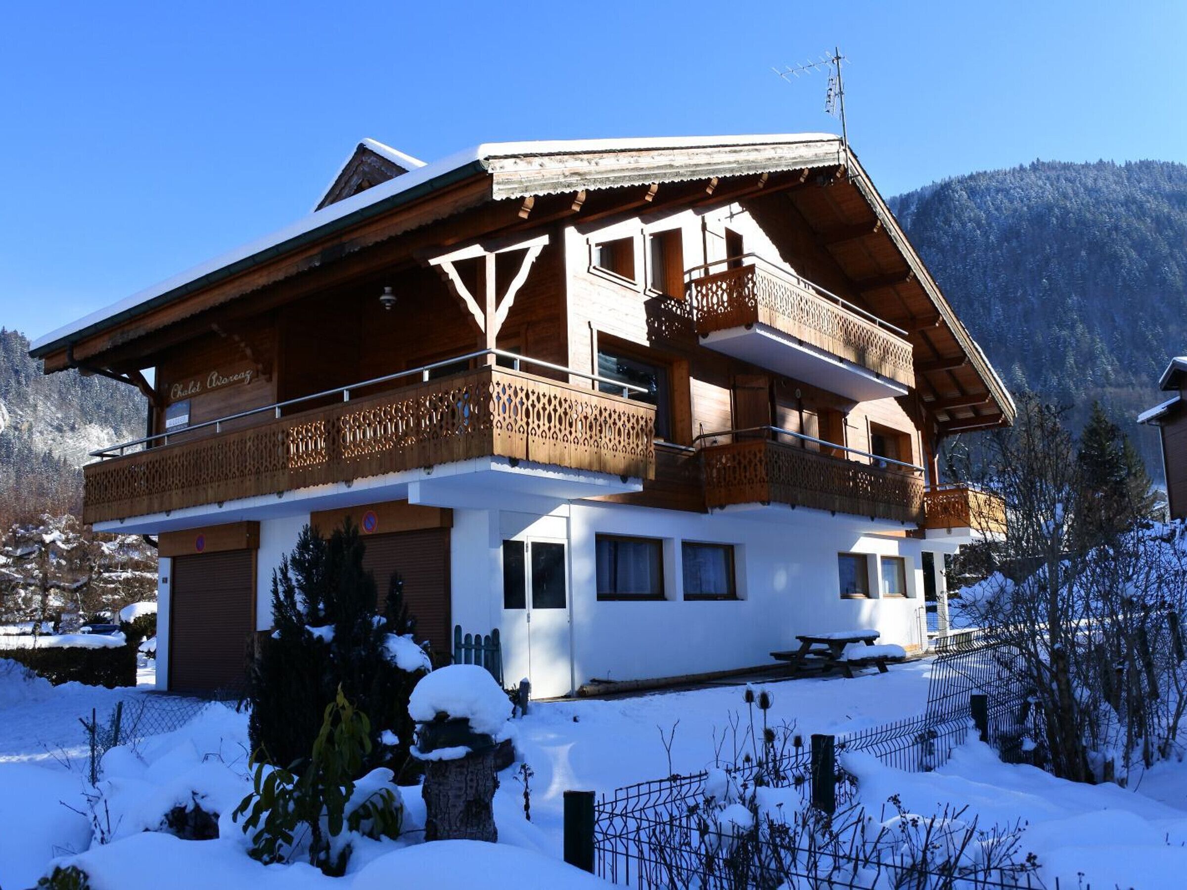 Un bâtiment de style chalet, avec une façade en bois, de nombreux balcons et un paysage enneigé.