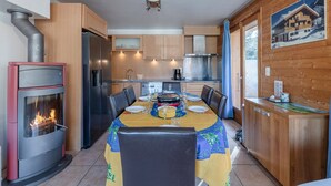 Una cocina acogedora con una isla central, una mesa de comedor para cuatro personas y un estufa de leña.