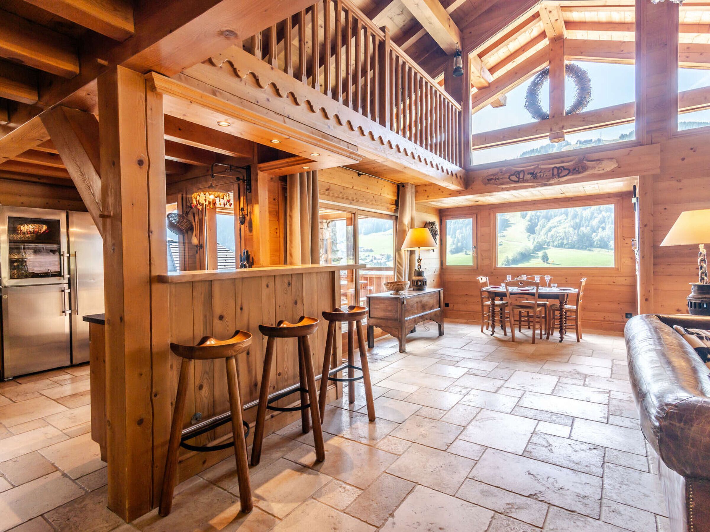 A wooden cabin interior with a kitchen, dining area, and bar.