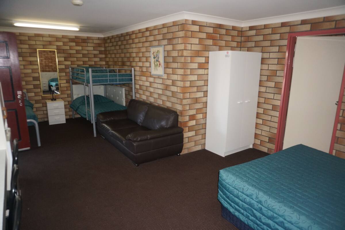 Ein Zimmer mit Etagenbett, einer Schlafcouch, einem Kleiderschrank, einem Spiegel und einer Tür.