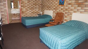 A hotel room with two beds, a desk, a chair, a small table, a mirror, and a picture on the wall. - Miles Outback Motel (Miles)