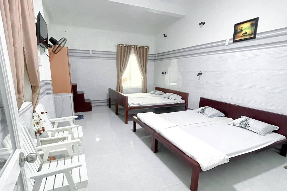 Une chambre d’hôtel avec deux lits, une télévision et une fenêtre avec des rideaux.