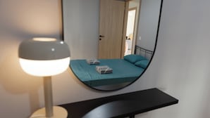 A bedroom with a bed, a bedside lamp, and a mirror reflecting the room. - Debbies apartment over the water! (Chalkida)