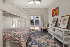 Un dormitorio con cama, una silla, un escritorio y una ventana con cortinas.