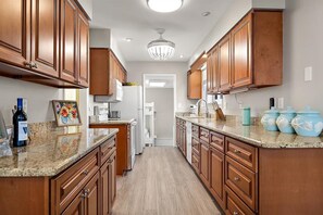 A kitchen with wooden cabinets, granite countertops, a refrigerator, a microwave, and a sink.