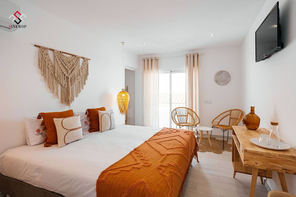 Une chambre d’hôtel moderne avec un grand lit, une table de chevet en bois et un téléviseur fixé au mur.