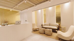 A modern reception area with a sofa, chairs, and a laptop on a counter. - Icon Mykonos (Mykonos)