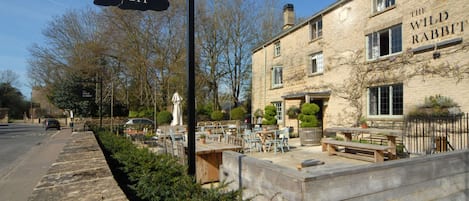 A building named 'The Wild Rabbit' with outdoor seating and a stone facade.