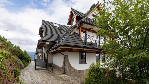 A two-story house with a stone facade, a wooden balcony, and a cobblestone driveway. - Cozy Apartment | With Mountain View and Balcony (Koscielisko)