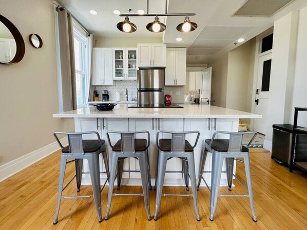 A modern kitchen with a central island, bar stools, and stainless steel appliances.