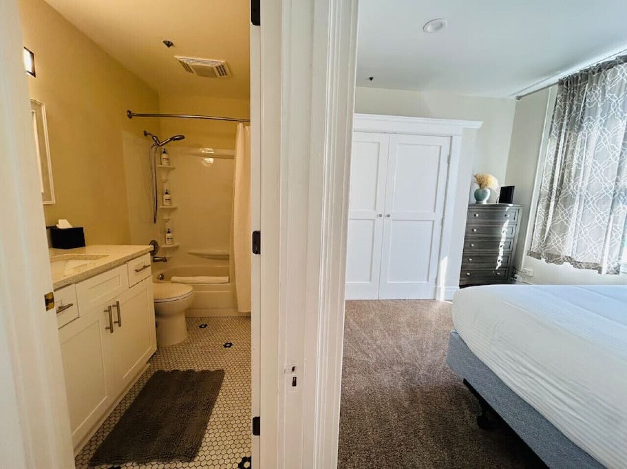 Una habitación de hotel con baño, cama, cómoda y armario.