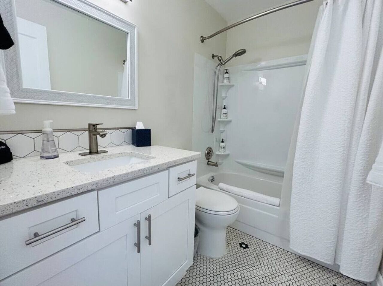 A bathroom with a sink, mirror, toilet, and shower.
