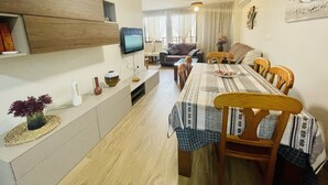 A dining area with a long table, chairs, and a television on the wall. - A1018 - Comfort and tranquility by the sea (Cala de Finestrat)