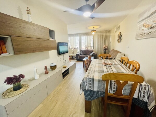 A dining area with a long table, chairs, and a television on the wall.