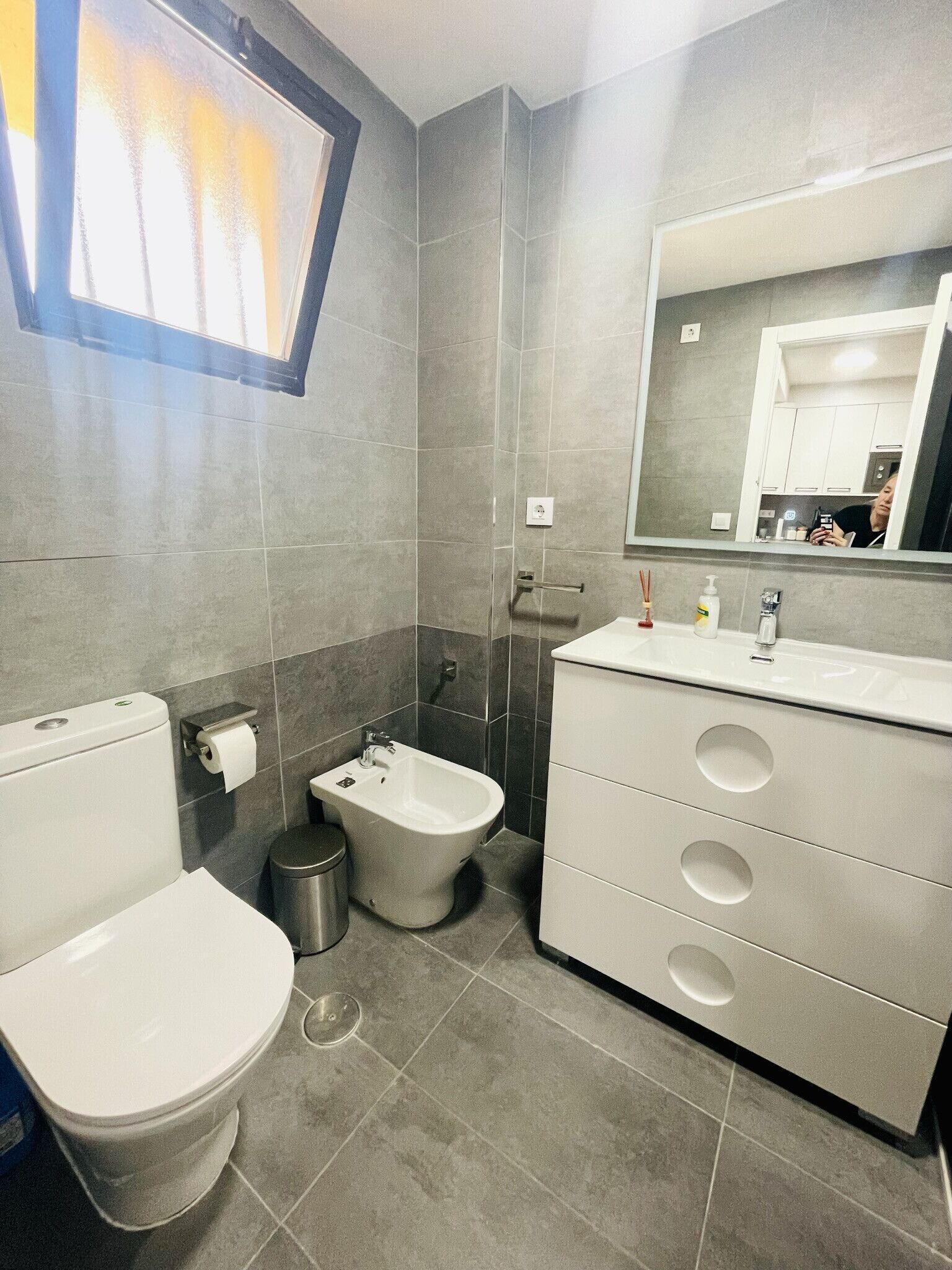 Un baño moderno con inodoro, bidé y tocador con cajones.