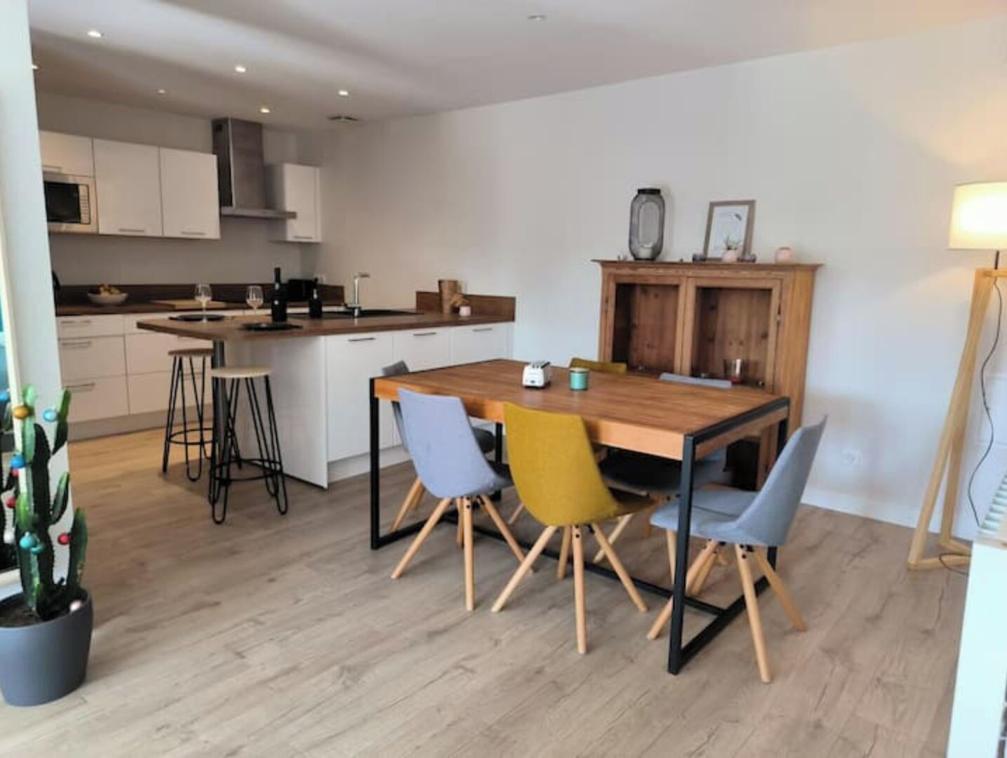 A modern kitchen with white cabinets, a wooden island, and a dining area with a wooden table and four chairs.