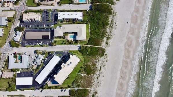 Vista aérea de una zona costera con edificios, una playa y una carretera.