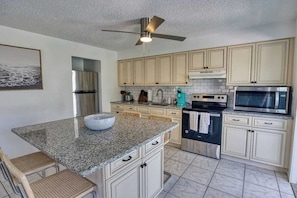 A kitchen with granite countertops, stainless steel appliances, and light-colored cabinetry. - Fillmore Unit #8 | 2BR/1BA (Cape Canaveral)