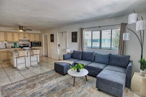 A modern living room with a grey sectional sofa, a round coffee table, and a patterned rug. - Fillmore Unit #8 | 2BR/1BA (Cape Canaveral)