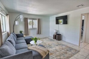 A modern living room with a grey sectional sofa, a small round coffee table, and a patterned rug. - Fillmore Unit #8 | 2BR/1BA (Cape Canaveral)