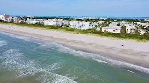 A beach with a clear view of the ocean and a row of buildings in the background.