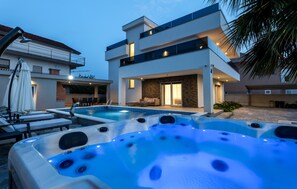 Ein modernes, zweistöckiges Haus mit Swimmingpool und zwei Whirlpools.