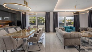 A modern dining area with a glass-top table, grey upholstered chairs, and a sofa with a teal throw. - Stunning home in Sukosan with WiFi (Sukosan)