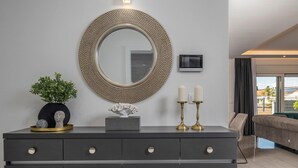 A modern living room with a dark grey console table, a round mirror with a textured frame, a small statue, and two candles. - Stunning home in Sukosan with WiFi (Sukosan)