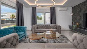 A modern living room with a grey sofa, teal armchair, and two round coffee tables. - Stunning home in Sukosan with WiFi (Sukosan)