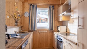 Cocina compacta con armarios de madera, un lavamanos, un microondas y un horno.