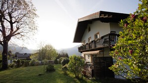 A two-story house with a balcony, surrounded by a well-maintained lawn and trees. - Alpenchalet Bad Reichenhall, flat for 2-4 pax, luxury interior, fantastic view (Bayerisch Gmain)