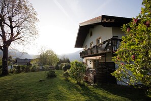 A two-story house with a balcony, surrounded by a well-maintained lawn and trees.