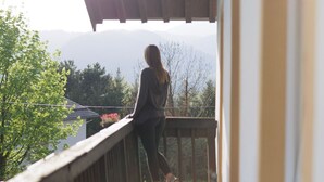 A person standing on a wooden deck with a view of mountains and trees. - Alpenchalet Bad Reichenhall, flat for 2-4 pax, luxury interior, fantastic view (Bayerisch Gmain)