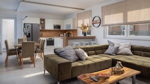 A modern living room with a sofa, coffee table, and dining area. - Villa Katarina Privlaka (Privlaka)
