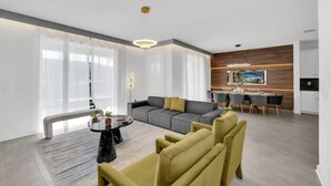 A modern living room with a grey sofa, yellow armchairs, a round coffee table, and a dining area with a white table and chairs. - Toy Story | Avatar | Mickey Theater | Waterpark 1135 (Davenport)